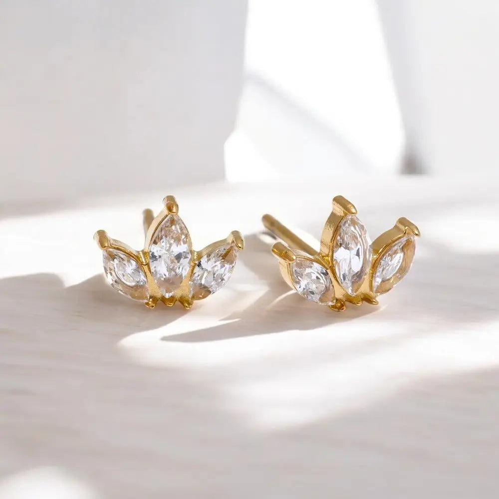 Gold earrings with clear gemstones on a light background