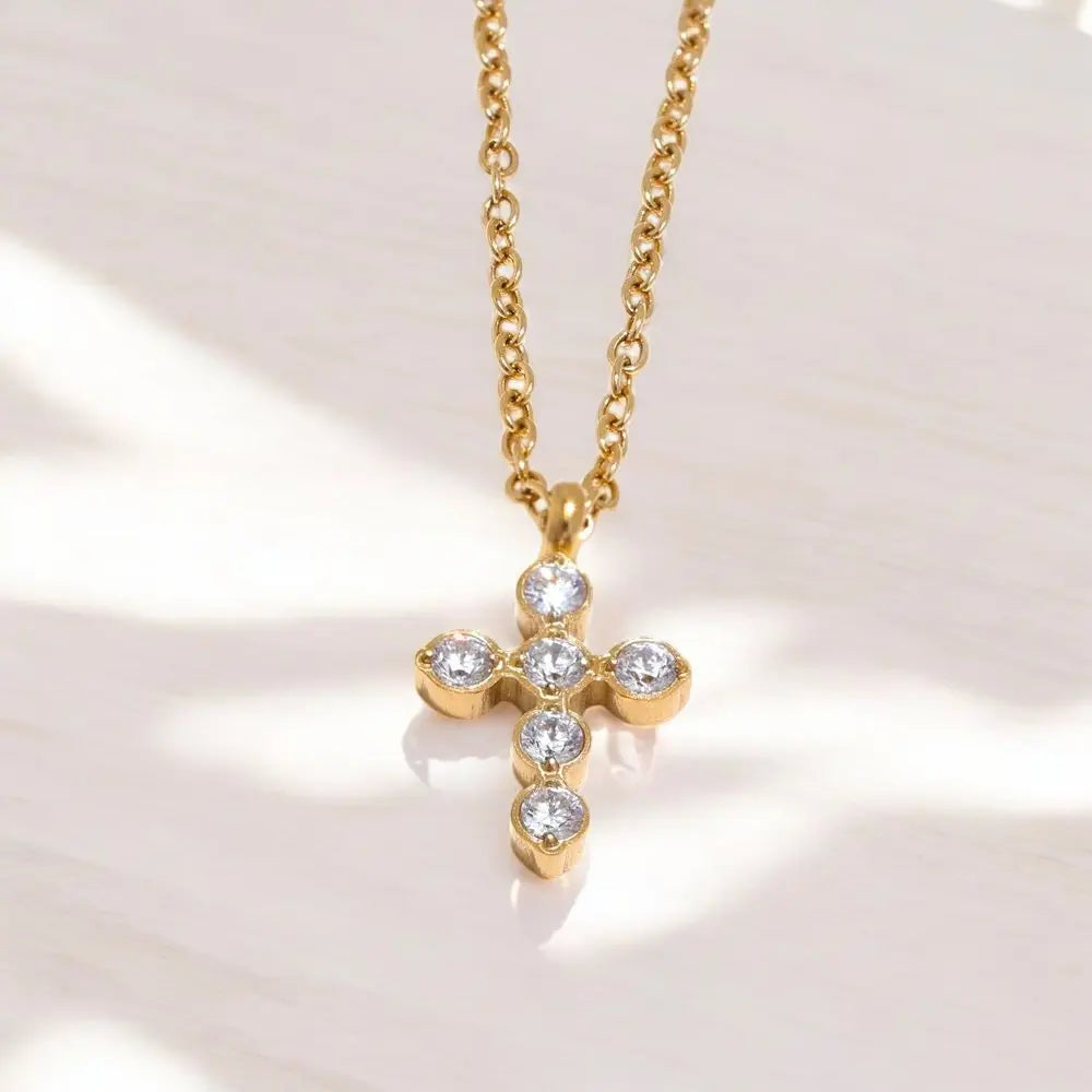 Gold cross necklace with diamonds on a light background