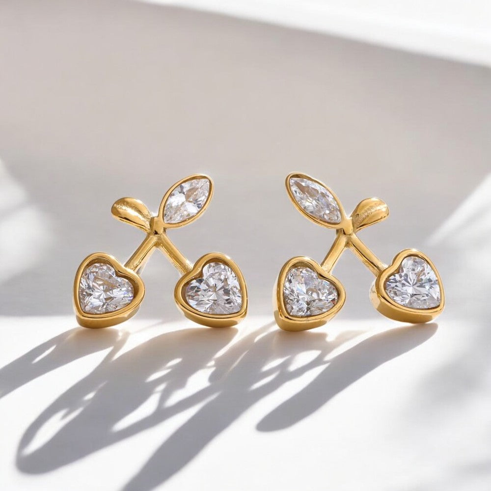 Pair of gold earrings with heart-shaped gemstones on a light background