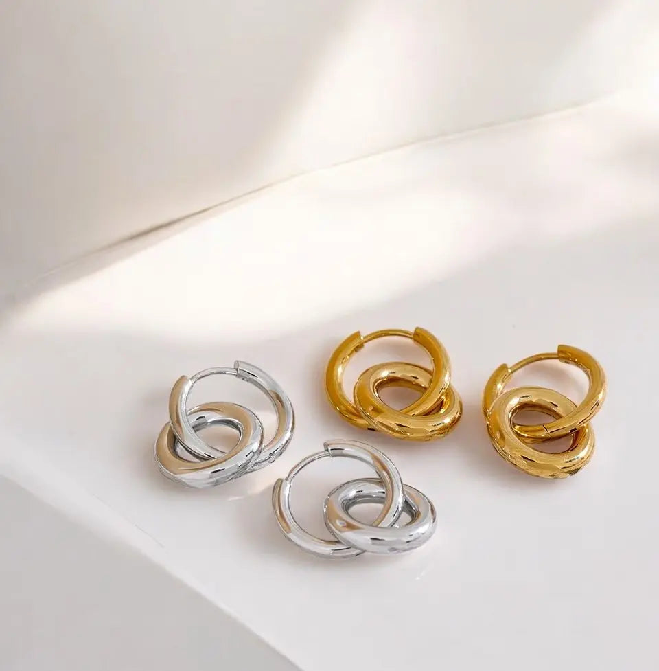 Pair of silver and gold hoop earrings on a light surface