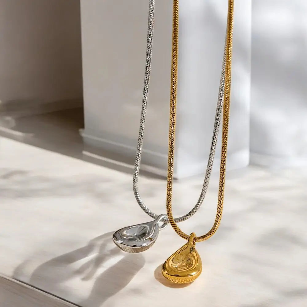 Two necklaces with teardrop pendants on a light surface