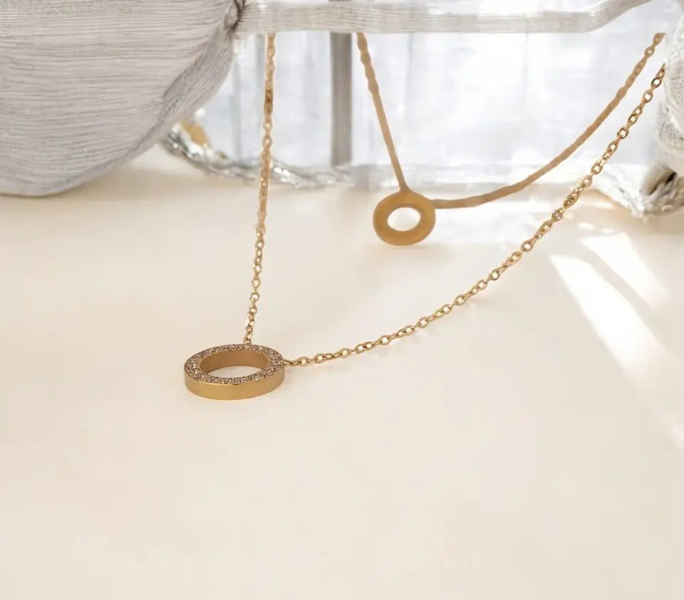 Gold necklace with circular pendant on a light surface