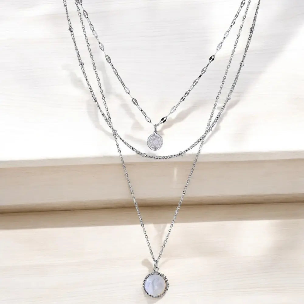 Two layered silver necklaces with pendants on a white background
