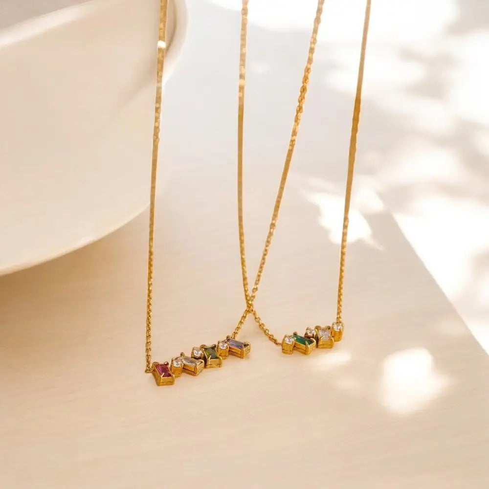 Gold necklaces with colorful gemstones on a light background