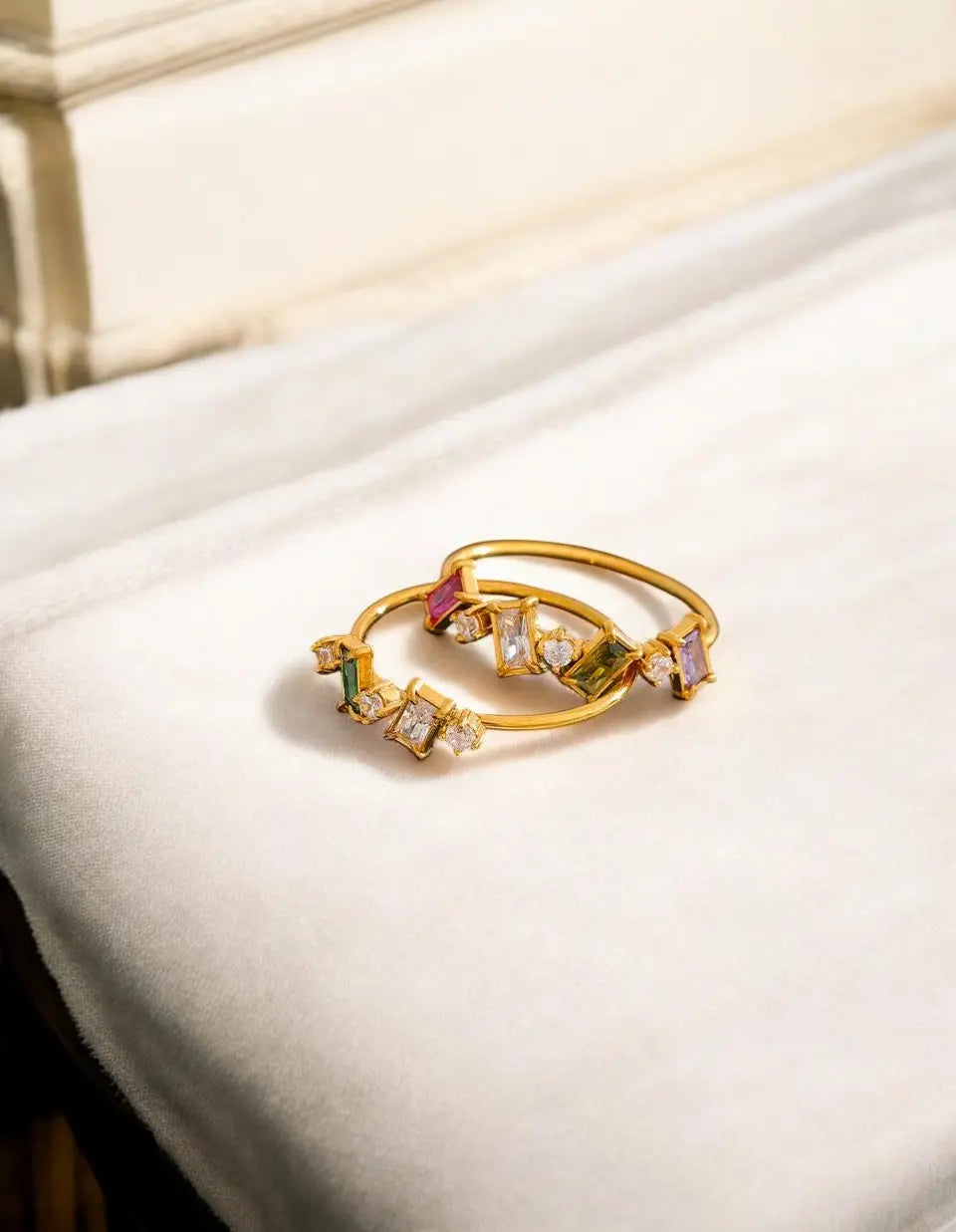 Gold ring with colorful gemstones on a white surface