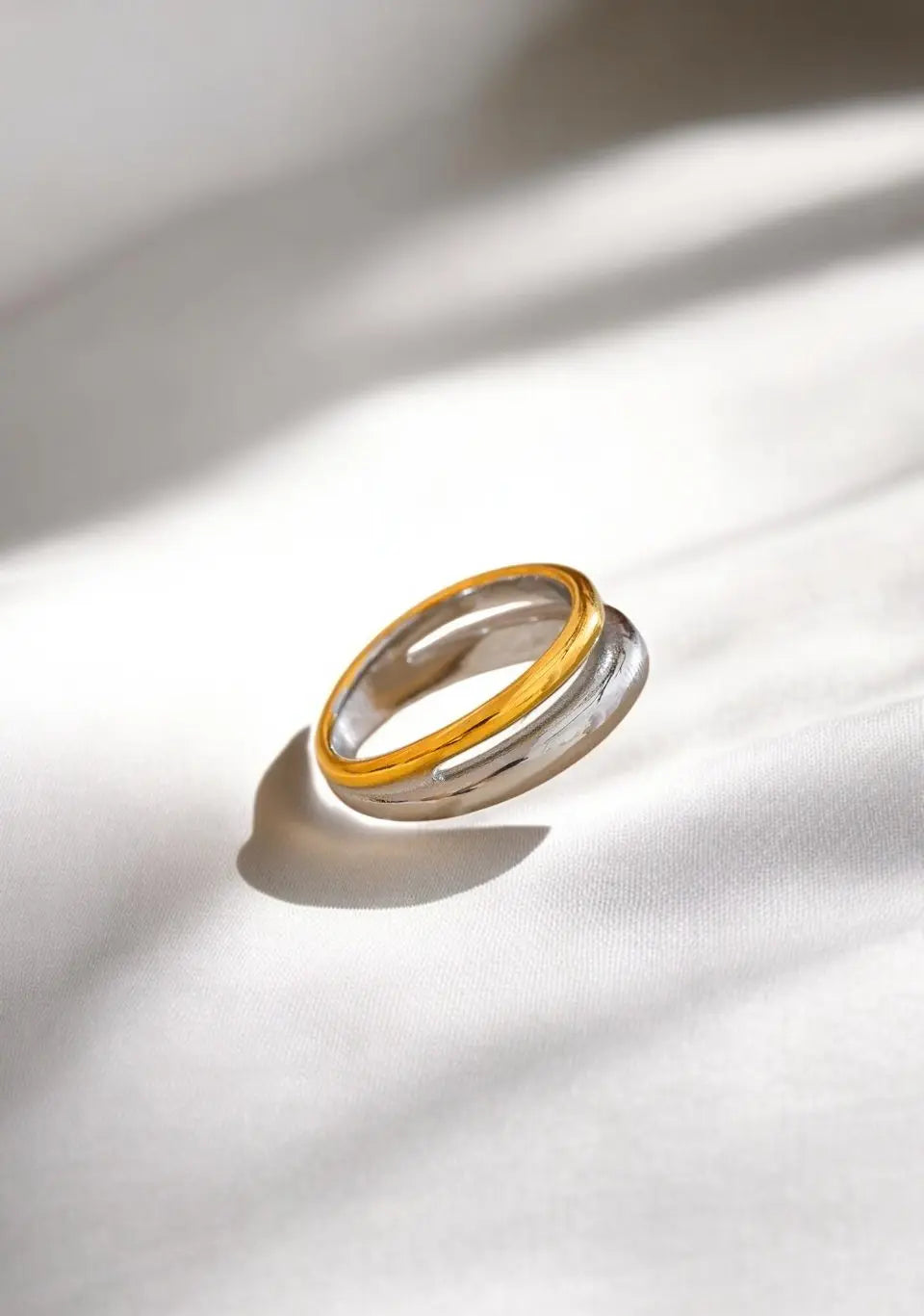 Two gold and silver rings stacked on a white fabric background