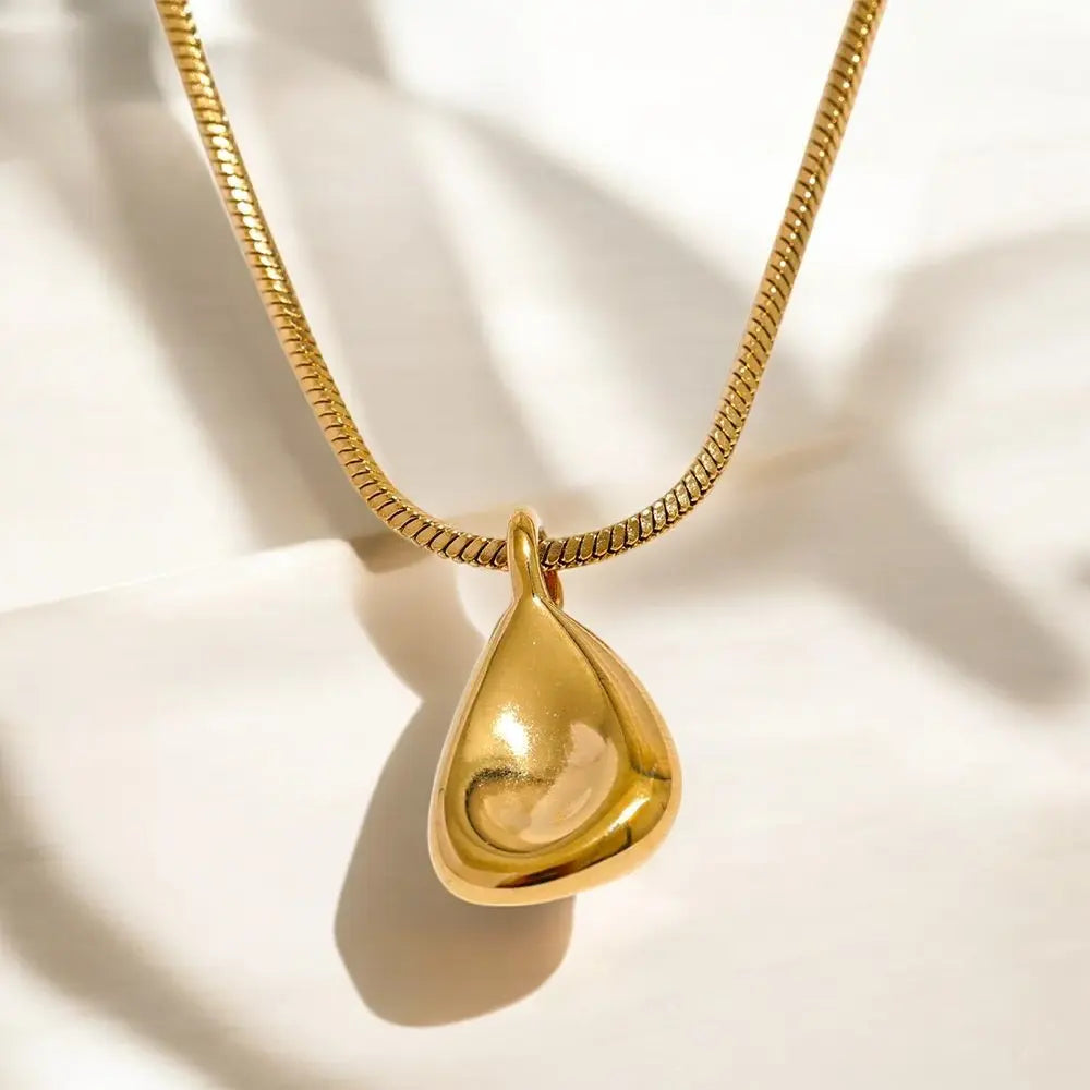 Gold necklace with a teardrop-shaped pendant on a light background