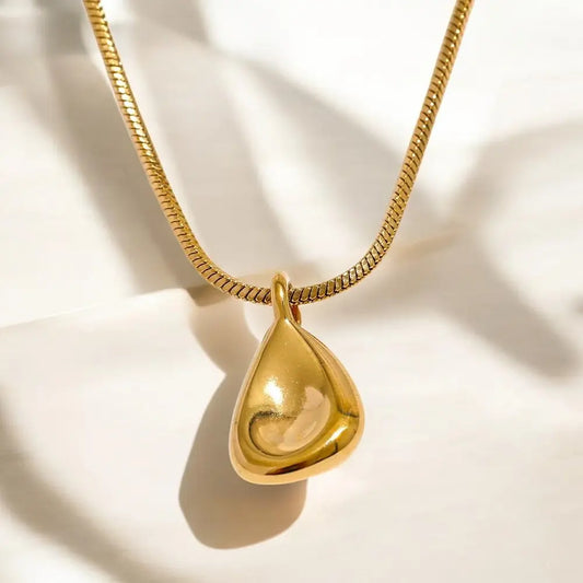 Gold necklace with a teardrop-shaped pendant on a light background