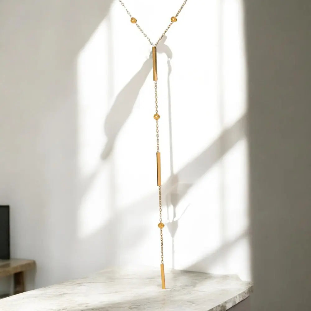 Gold necklace with beads on a marble surface with a light background