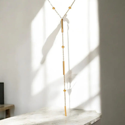 Gold necklace with beads on a marble surface with a light background