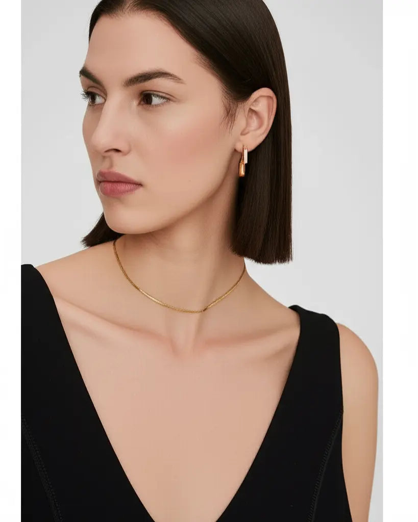 Woman wearing a gold necklace and earrings on a plain background