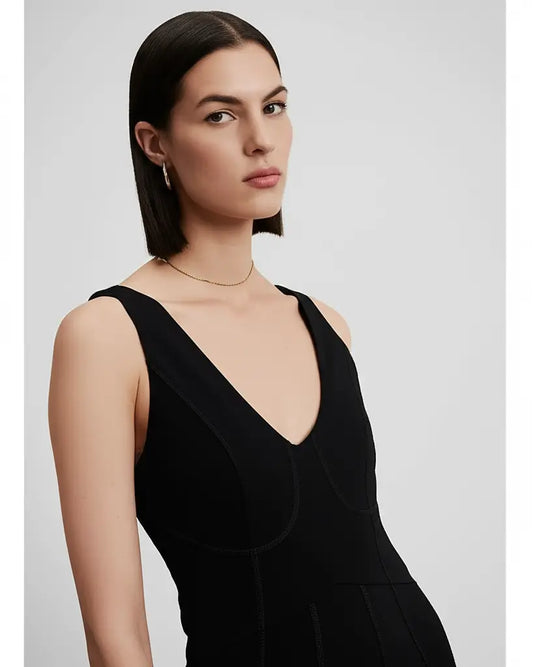Woman wearing a black sleeveless dress against a light gray background