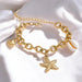 Gold chain bracelet with starfish charm on a white fabric background