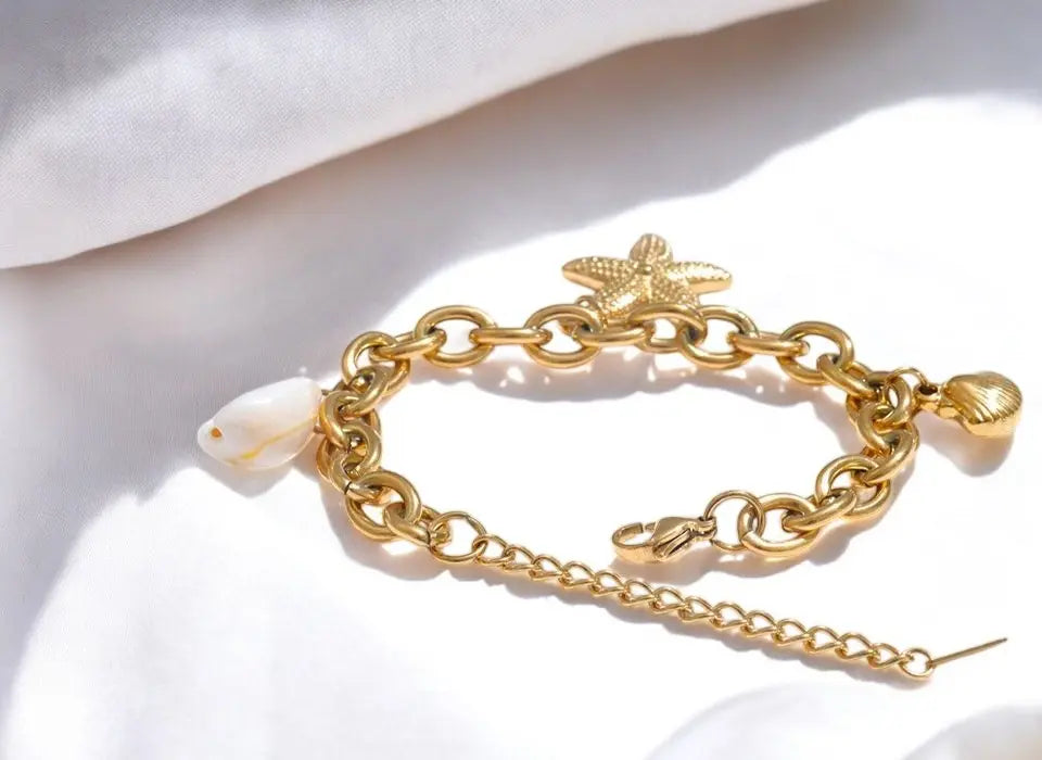 Gold chain bracelet with starfish charm on a white background