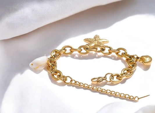 Gold chain bracelet with starfish charm on a white background