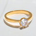 Gold ring with a clear gemstone on a light gray background