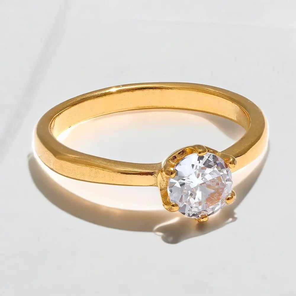 Gold ring with a clear gemstone on a light gray background