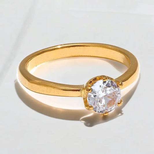 Gold ring with a clear gemstone on a light gray background