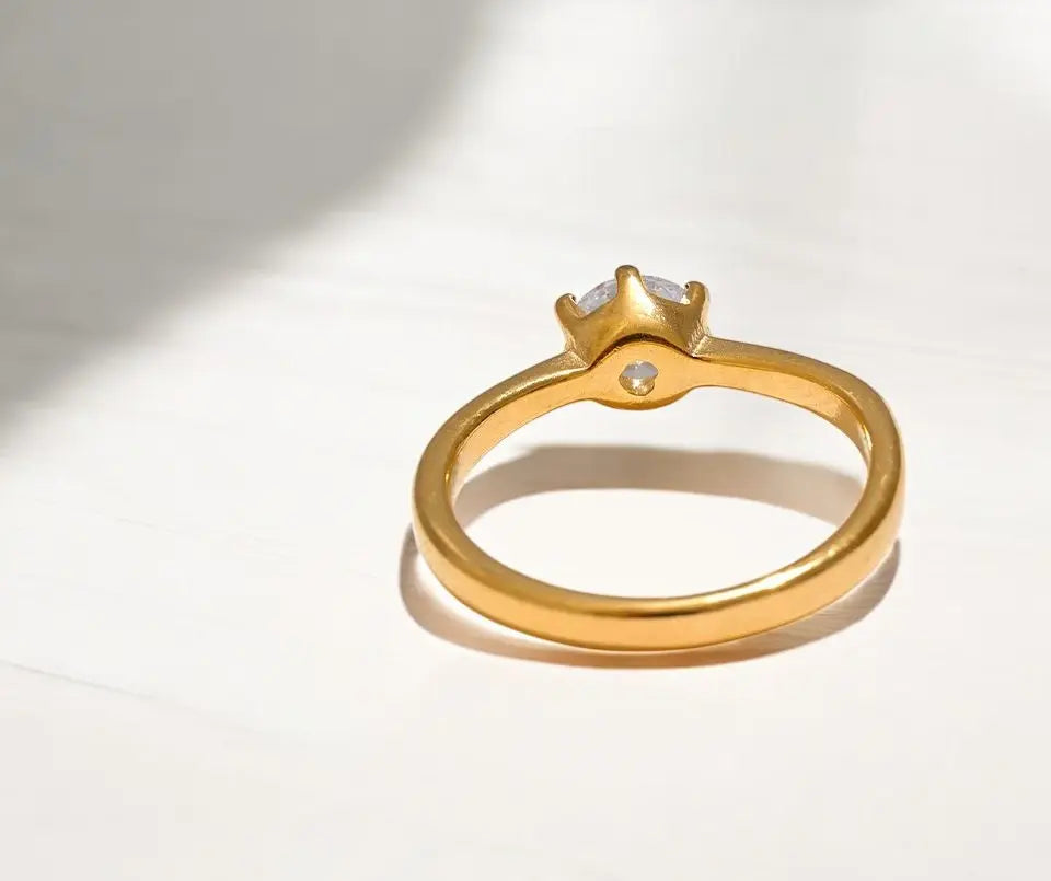 Gold ring with a diamond on a light gray background