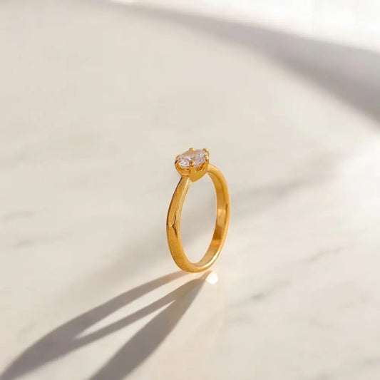 Gold ring with a diamond on a light beige background