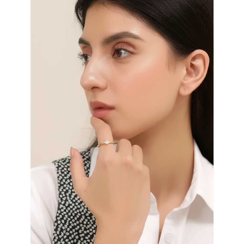 Close-up of a woman wearing a gold ring on her finger against a neutral background