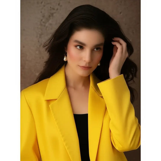 Woman wearing a bright yellow blazer against a neutral background
