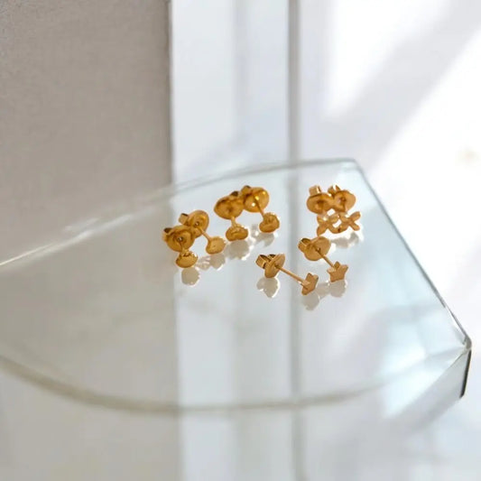 Gold floral earrings on a clear stand with a white background