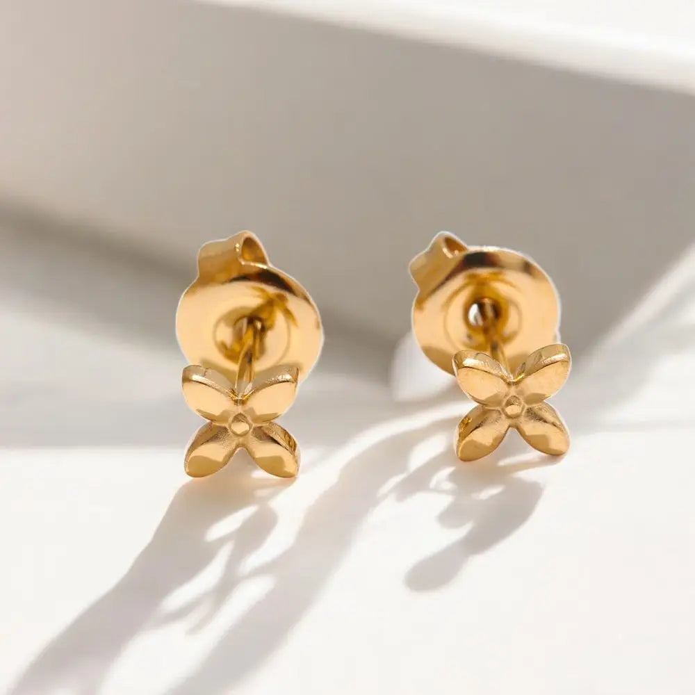 Gold bow-shaped earrings on a light background