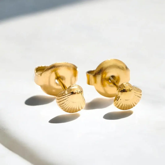 Pair of gold shell-shaped earrings on a light background