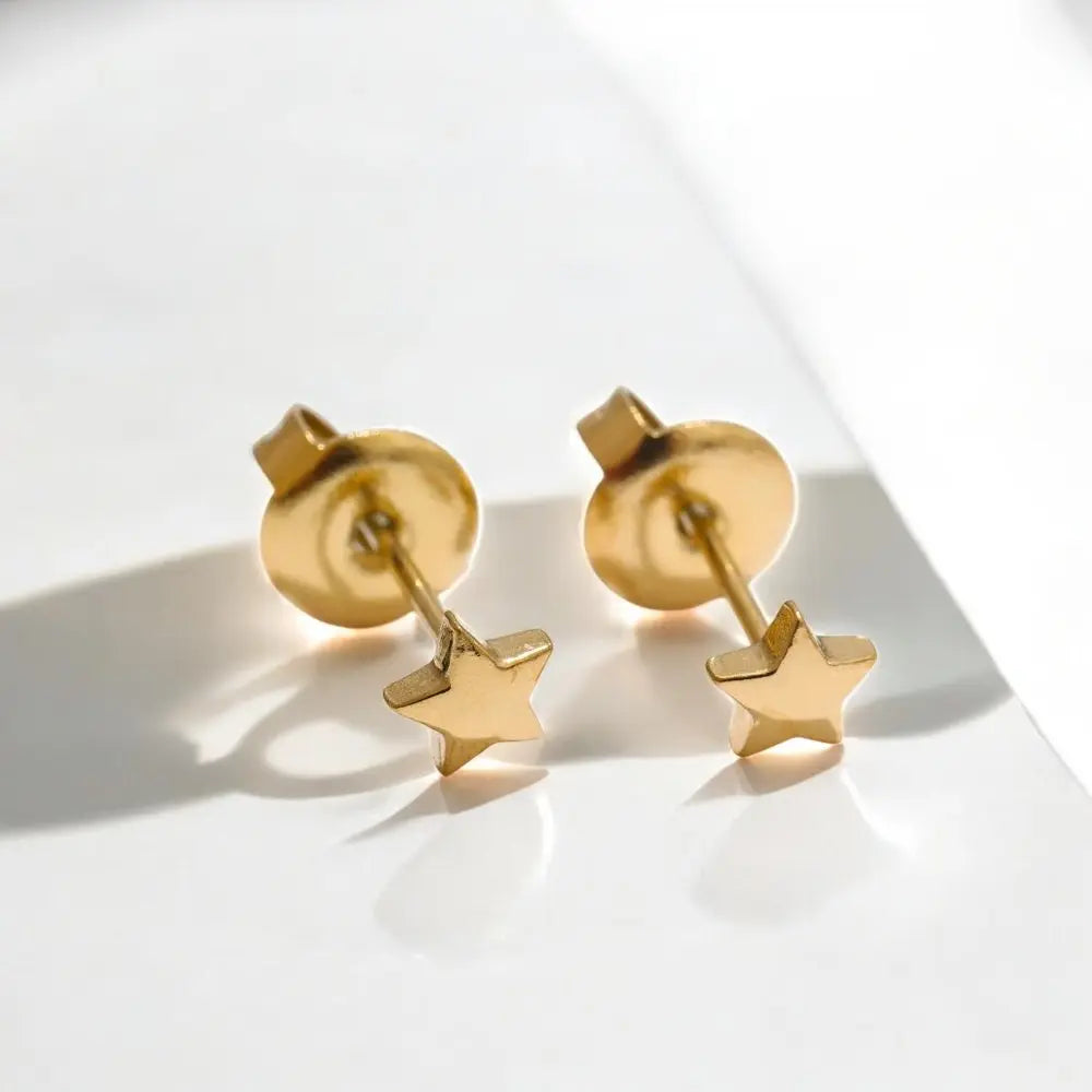 Gold star earrings on a light background
