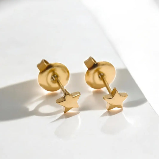 Gold star earrings on a light background