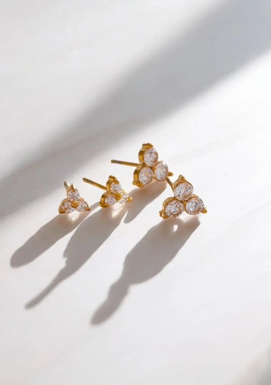 Gold earrings with clear gemstones on a light background