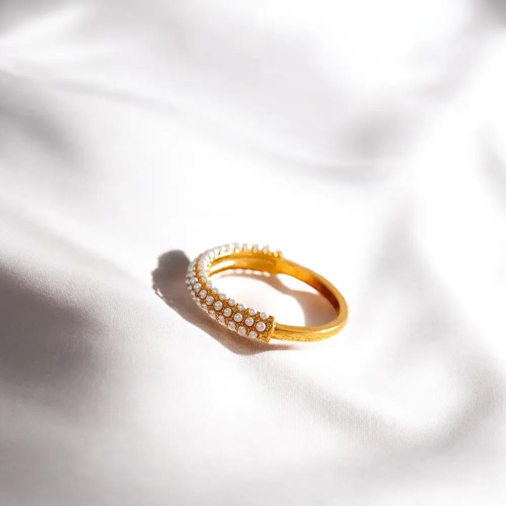 Gold bracelet with embedded stones on a white fabric background