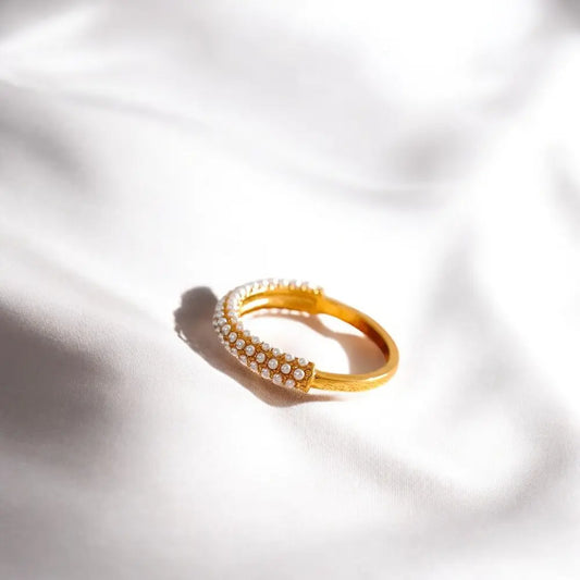 Gold bracelet with embedded stones on a white fabric background