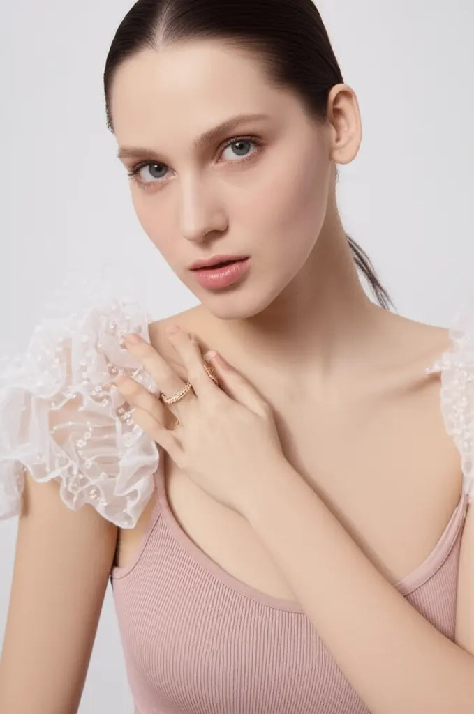 Woman wearing a pink top with lace sleeves against a light background