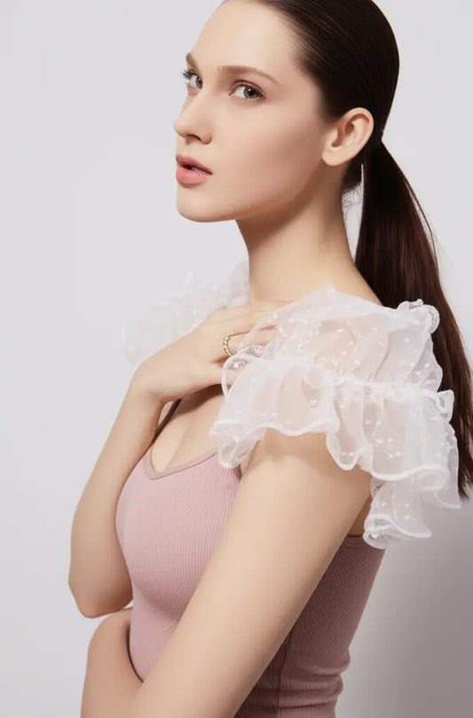 Woman wearing a pink top with sheer white sleeves against a light background
