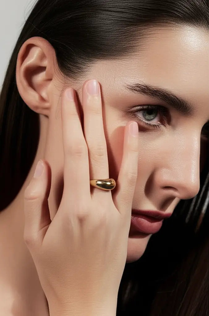 Close-up of a woman's face with a hand touching her cheek, wearing a gold ring.