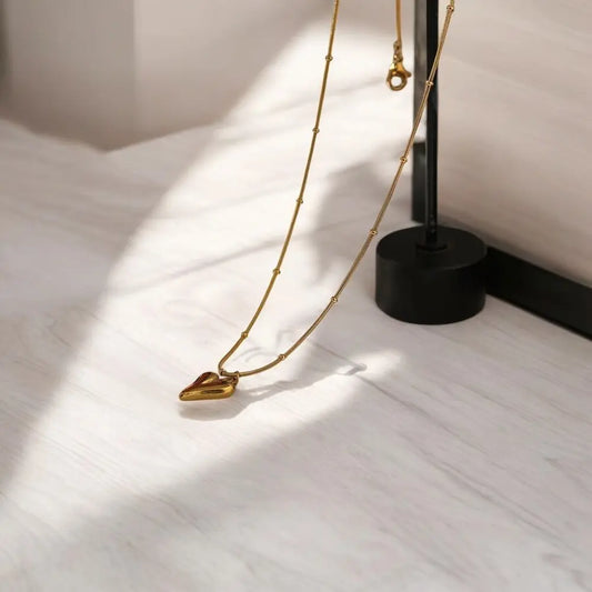 Gold necklace with a unique pendant on a white surface