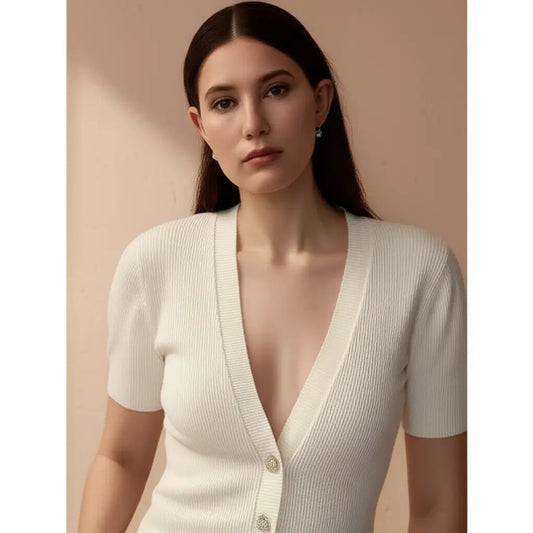 Woman wearing a white ribbed cardigan against a beige background