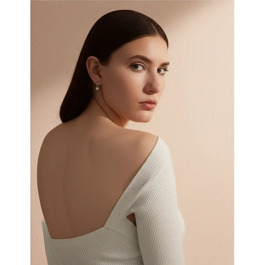 Woman wearing a white off-shoulder top against a beige background