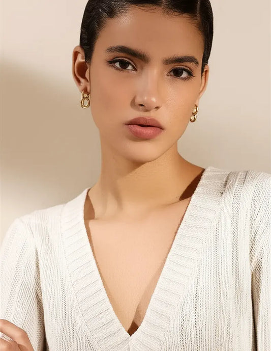 Woman wearing a white sweater with a plain background