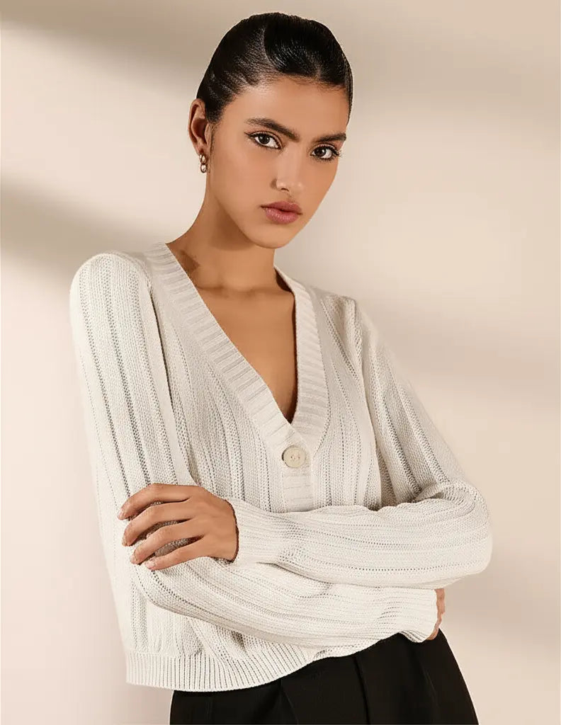Woman wearing a white ribbed sweater against a beige background