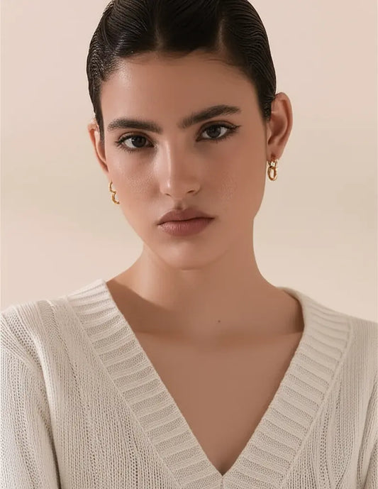 Woman wearing a beige knitted sweater with a plain background