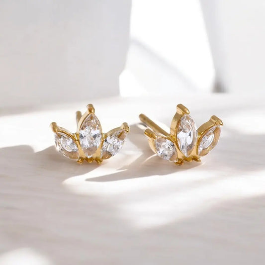 Gold earrings with clear gemstones on a light background