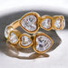 Gold ring with heart-shaped diamond stones on a reflective surface