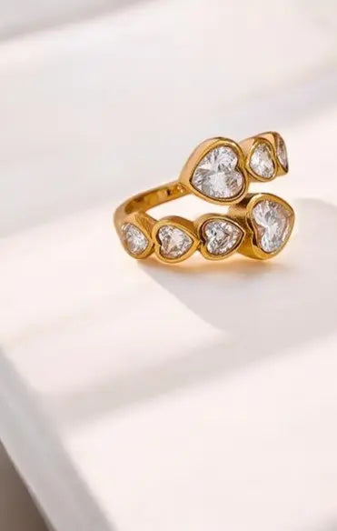 Gold ring with heart-shaped gemstones on a light background