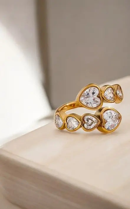 Gold ring with heart-shaped gemstones on a light background