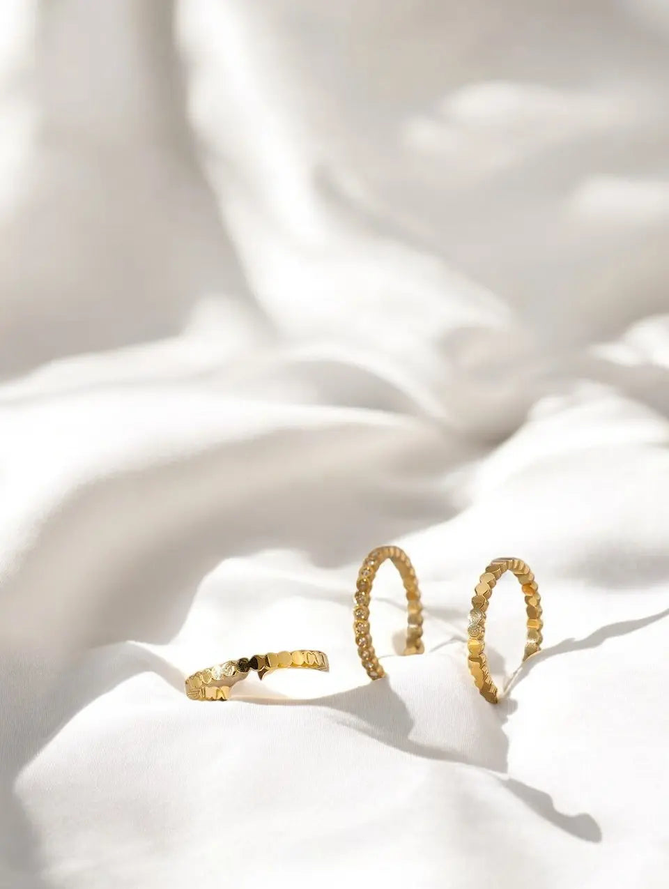 Gold hoop earrings on a white fabric background