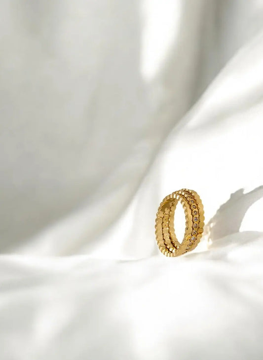 Gold ring with a textured band on a white fabric background