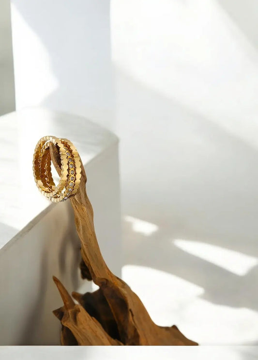 Gold bracelet on a wooden surface with a white background